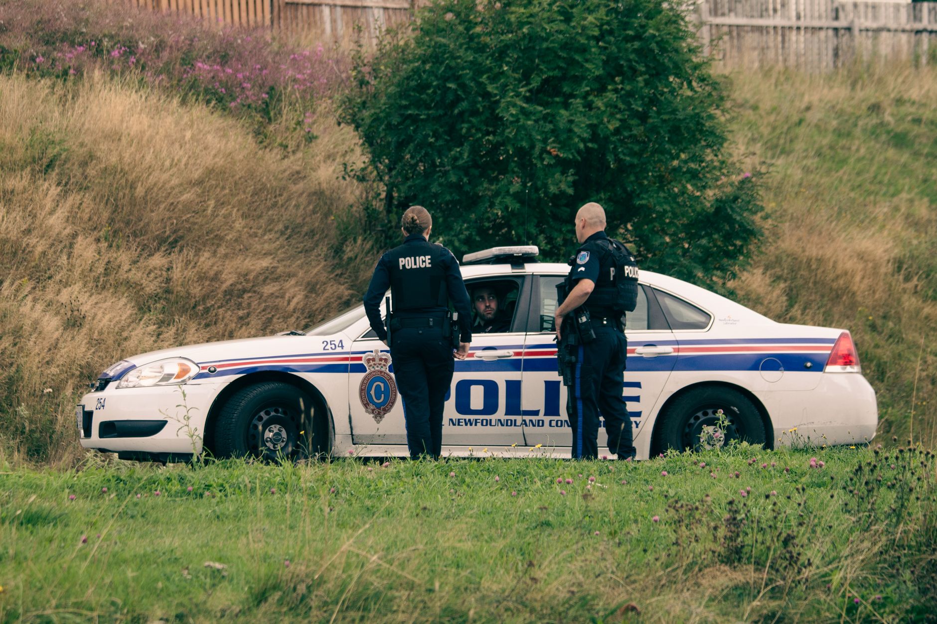 Two officers standing beside a marked patrol car